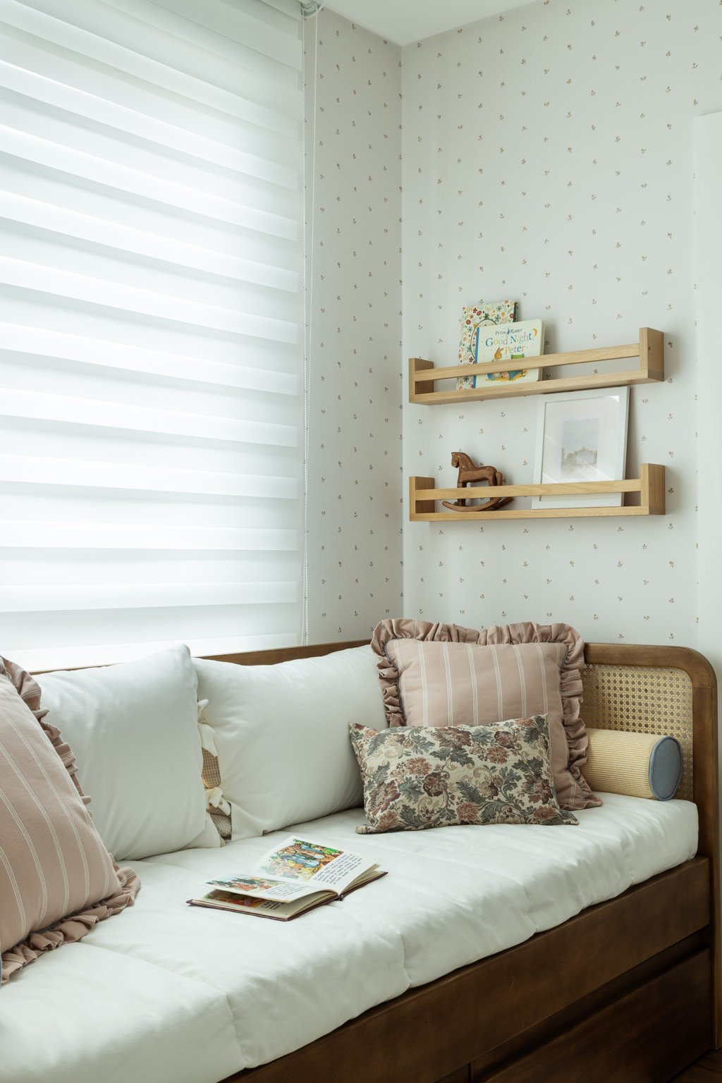 Cama auxiliar e prateleira com livros infantis que fazem parte do projeto de quarto de bebê completo da pequena Olívia.