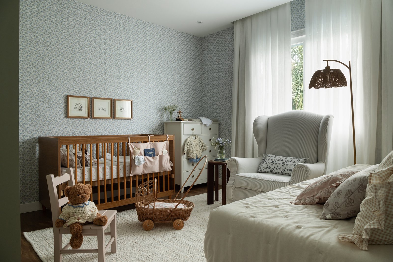 Visão da porta do quarto de bebê da Mel, com berço, cômoda e poltrona de amamentação.