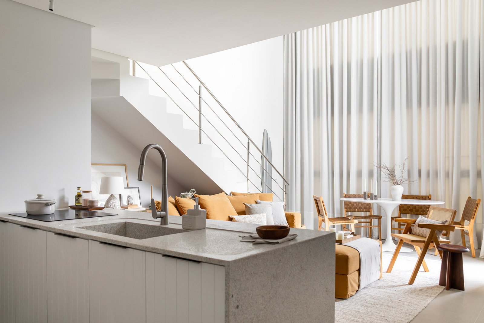Visão do térreo de um loft com mezanino. Nessa imagem aparece a área social do local, com cozinha, living e jantar.