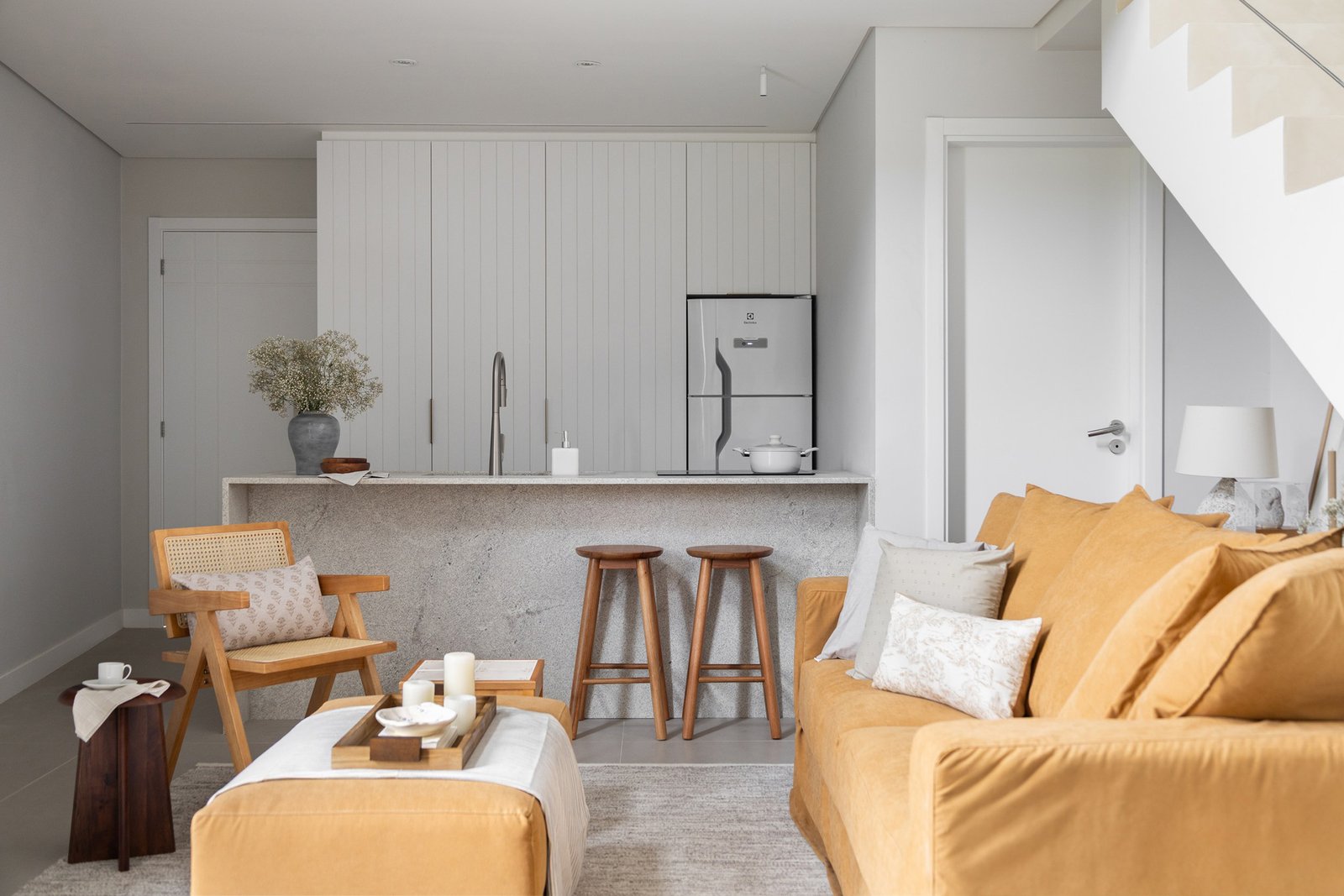 Área social integrada com o living e a cozinha ao fundo em um loft com mezanino localizado em Florianópolis.