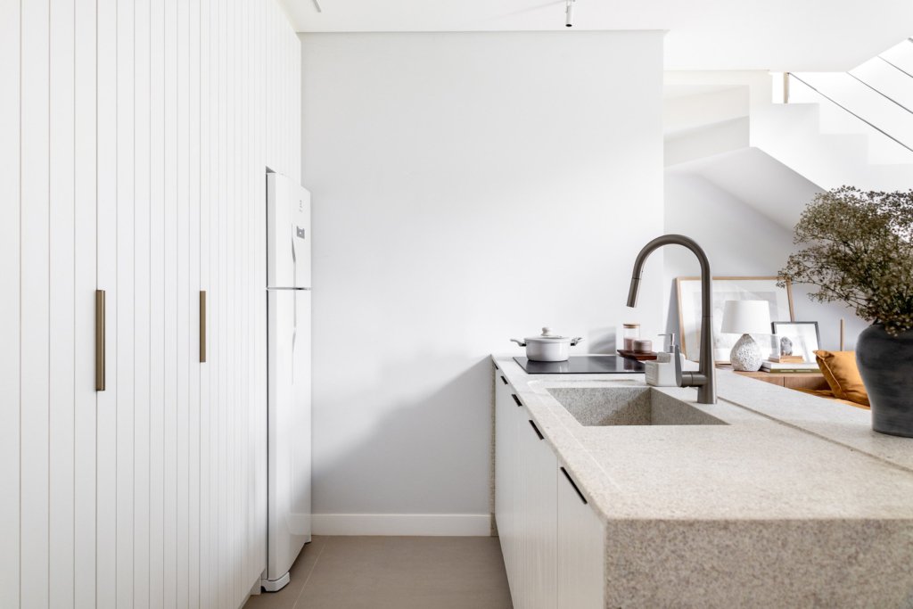 Cozinha compacta e funcional de um loft com mezanino.